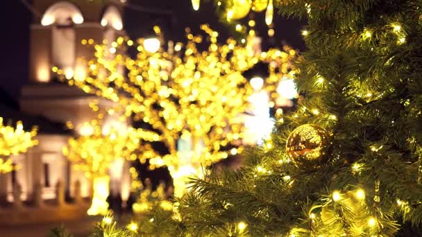 Cierra las luces de un árbol de Navidad brillando por la noche. El abeto de Año Nuevo con adornamientos y la iluminación. Fondo decoraciones árbol de Navidad. Muchas grandes bolas de oro en abeto Año Nuevo y Navidad - Imágenes, Vídeo
