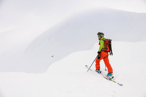 view of man skier with trekking poles walking along snowy mountain slope - Valokuva, kuva