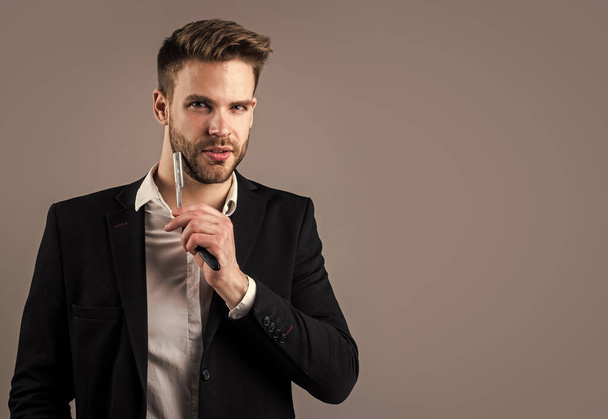 young handsome guy in suit hold razor blade. male barber master with tool. bearded man with business look. fashion and beauty. barbershop concept. mens hair styling and grooming - 写真・画像