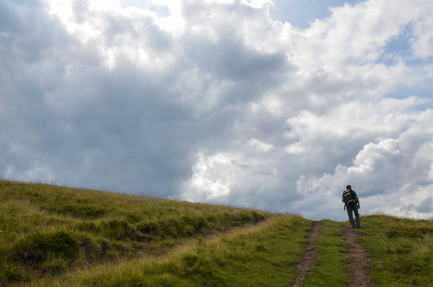 Wandelaar met rugzak achter de horizon op wandelpad boven de wolken. Ontdekken en avontuur concept - Foto, afbeelding