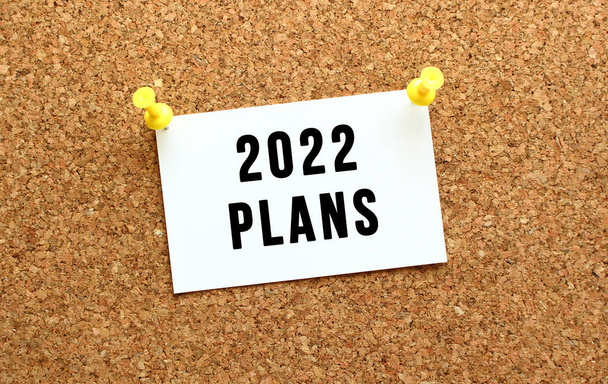 2022 PLANS está escrito en una tarjeta adjunta al corcho con un botón. Recordatorio en el tablero de la oficina. Concepto empresarial. - Foto, imagen