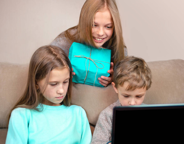 Two girls and one boy look at a laptop and communicate with the interlocutor online. Congratulations on the holiday online. - Fotó, kép