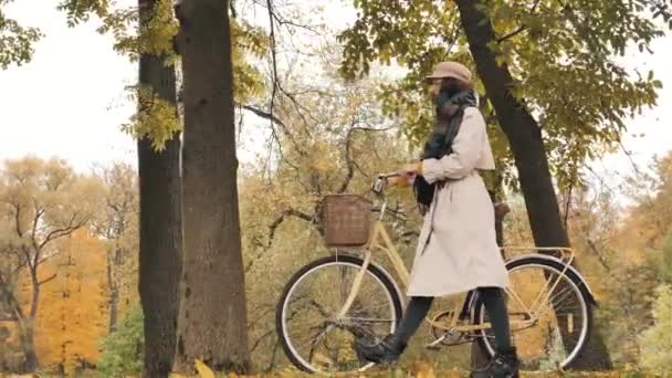 Молода жінка гуляє з велосипедом проти жовтих дерев у парку
 - Кадри, відео