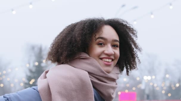 Yakın plan güzel, melez, Afro-Amerikan kadın bayan bayan bayan öğrenci gülümsemesi takıyor soğuk mevsimde şehir sokaklarında eşarp stantları kışın gökyüzüne bakıp gülümsüyor ve kameraya bakıp gülüyor. - Video, Çekim