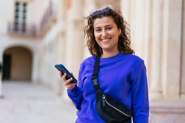 Smiling woman with smartphone on street - Foto, afbeelding