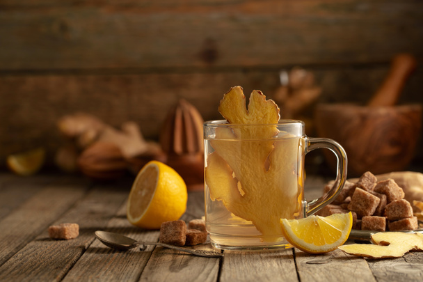 Tè allo zenzero con ingredienti. Zenzero, limone e zucchero di canna su un vecchio tavolo di legno. - Foto, immagini