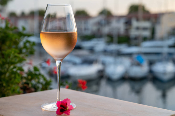 夏の日没時に地元の冷たいバラのワインの試飲、バックグラウンドでポートグローの帆船の避難所、プロバンス、ヴァール、フランス - 写真・画像