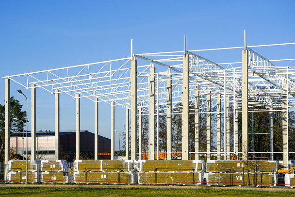 新しい近代的な未完成の工業ビルの建設現場の鉄筋コンクリート製の支持体上の金属フレーム構造 - 写真・画像
