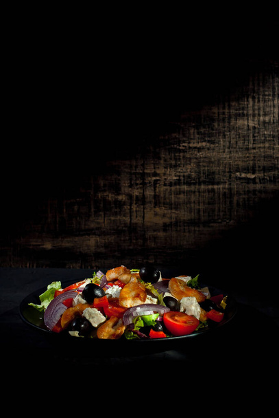 Salad with tomatoes, peppers, olives and chicken fillet. Fresh salad in a black plate on a dark background. Copy space and free space for text near food. - Foto, afbeelding