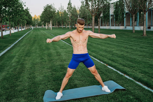 athletic man in blue shorts working out in the park - Photo, Image