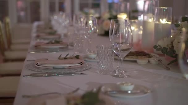 Served table in a restaurant for dinner, lunch or celebration. Decorated flowers - Materiał filmowy, wideo