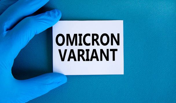 New covid-19 omicron variant strain symbol. Hand in blue glove with white card. Concept words Omicron variant. Medical and COVID-19 omicron variant strain concept. Copy space. - Photo, image