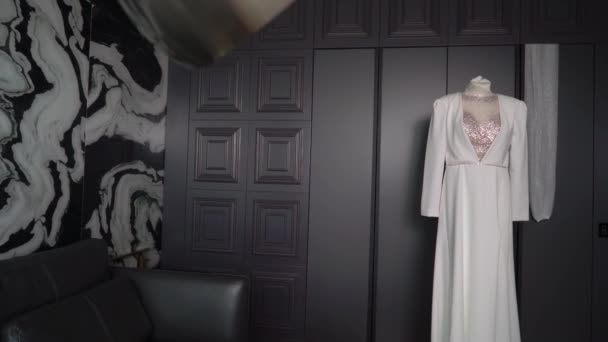 Wedding dress, white bridal gown hanging on hanger in bedroom. - Filmagem, Vídeo