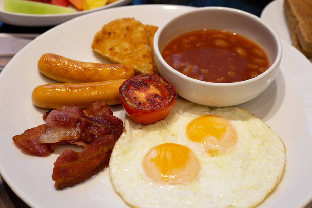 Gebratene Eier, Speck, Würstchen, Bohnen, Tomaten zum Frühstück. - Foto, Bild