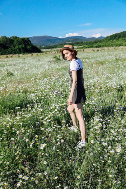 beautiful woman travels walking a field of daisies - Фото, изображение