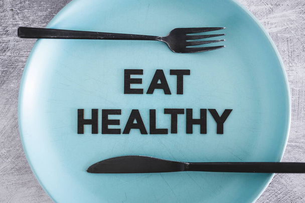 eat healthy text on dining plate with fork and knife, concept of dieting vs healthy nutrition and intuitive eating - Foto, immagini