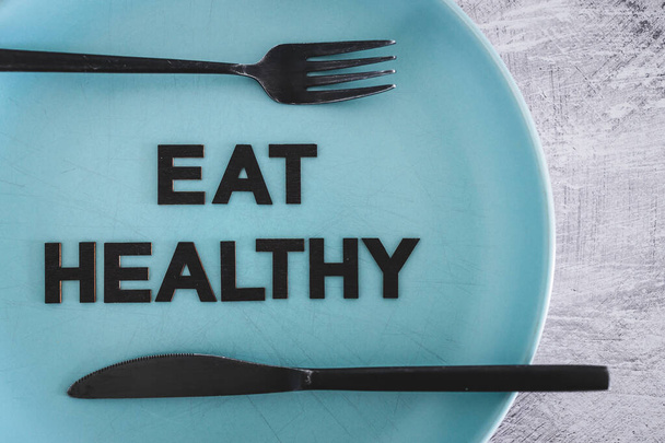 eat healthy text on dining plate with fork and knife, concept of dieting vs healthy nutrition and intuitive eating - Foto, immagini