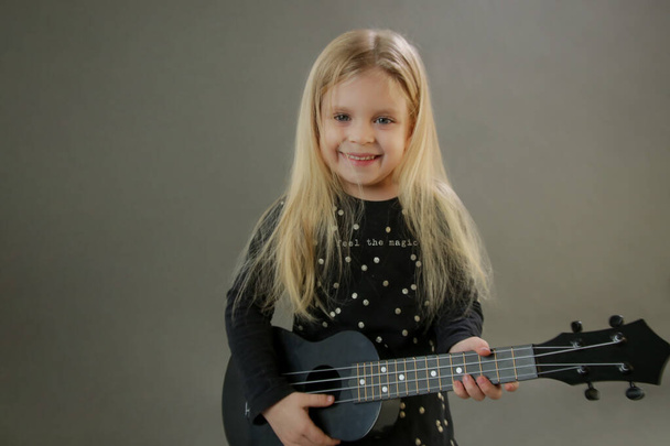 Estúdio retrato de adorável menina jogar ukulele - Foto, Imagem