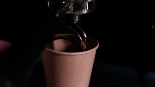 Fekete kávé ömlik a professzionális kávéfőzőből. Kávét főz a barista. Sötét loft kávézó. lassított felvétel - Felvétel, videó