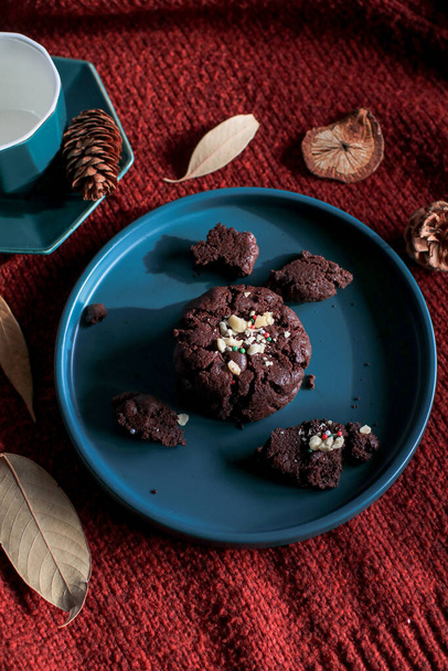 Yeşil tabakta çikolatalı Noel kurabiyeleri, kırmızı arka plan. Sıcak ev atmosferi. Şenlikli ev yapımı tatlılar. - Fotoğraf, Görsel