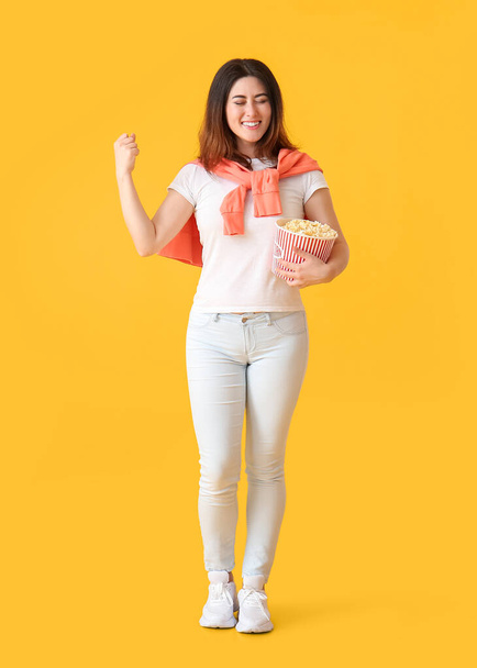 Felice giovane donna asiatica con secchio di popcorn gustosi su sfondo giallo - Foto, immagini