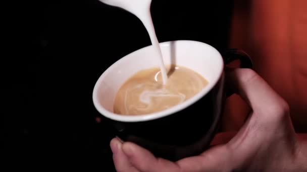 latte art by barista. nalévání mléka do kávy. tmavá kavárna. zpomalený pohyb - Záběry, video