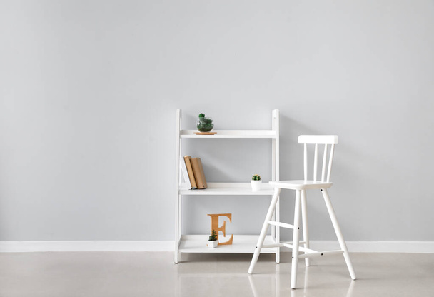 Білий стілець і книжкова шафа біля світлої стіни
 - Фото, зображення