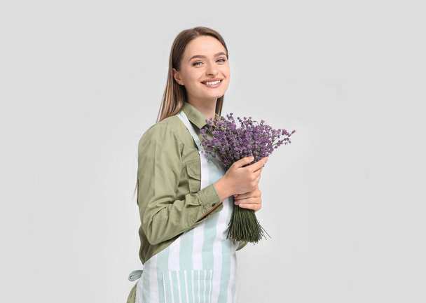 Female gardener with lavender on light background - Foto, Imagen