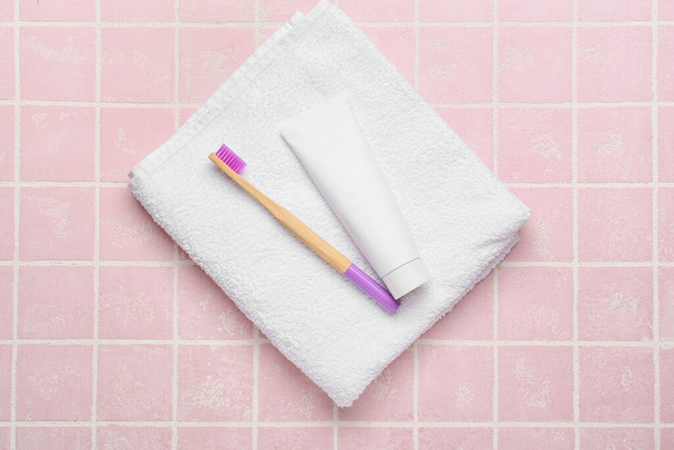 Dřevěný kartáček na zuby s pastou a měkkým ručníkem na barevném pozadí - Fotografie, Obrázek