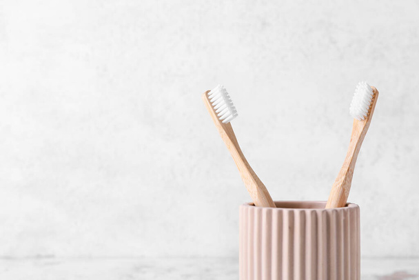 Holder with wooden toothbrushes on light background, closeup - Photo, Image