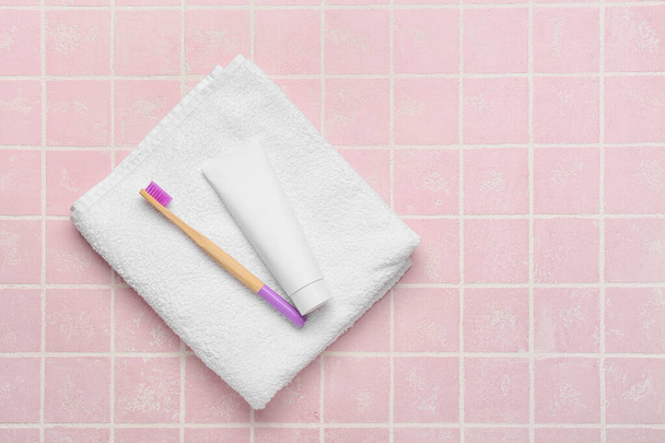 Drewniana szczoteczka do zębów z pastą i miękkim ręcznikiem na tle koloru - Zdjęcie, obraz