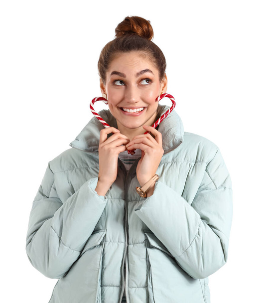 Onnellinen nuori nainen talvivaatteissa ja karkkia keppejä valkoisella taustalla - Valokuva, kuva
