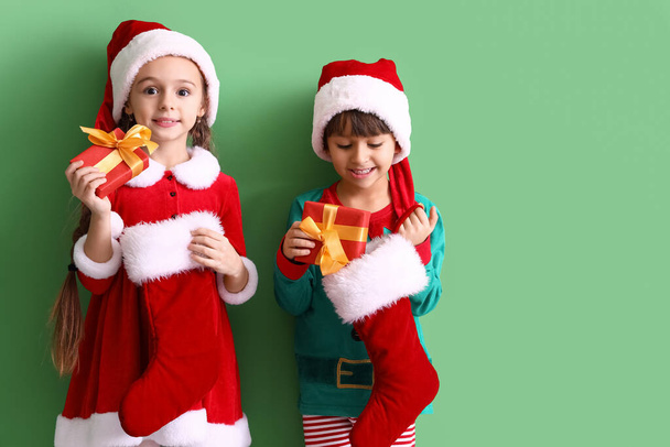 Cute little children with Christmas socks and gifts on color background - Photo, Image