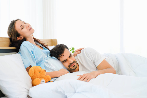 portrait of happy pregnant wife and husband lying together on bed in bed room at home - Photo, Image