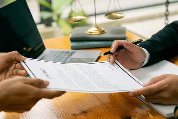 Anwälte und Mandanten halten Dokumente im Büro. Bild eines Unternehmeranwalts mit einem Vertragsdokument, einem Kooperationsvertrag mit einem Mandanten und einem Hammer auf dem Tisch. - Foto, Bild