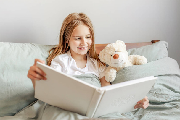 Child girl with teddy bear toy in the bed - Fotó, kép
