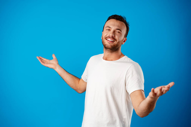 Portrait of confused man giving I dont know gesture over blue background - Photo, image