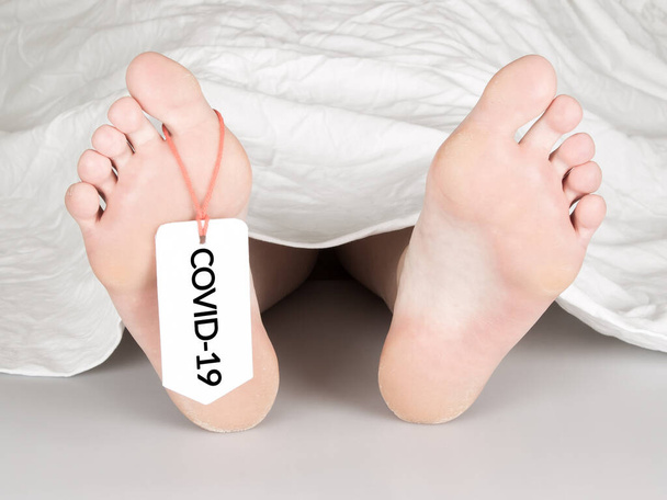 Körper mit Zehenanhänger auf weiß, unter weißem Laken - Covid-19 - Foto, Bild