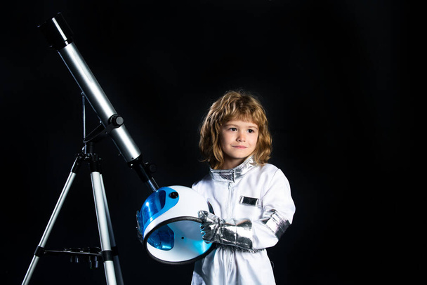 Small child wants to fly an in space, kid boy with telescope wearing an astronaut helmet. Copy space. Success, creative and start up concept. - Фото, зображення