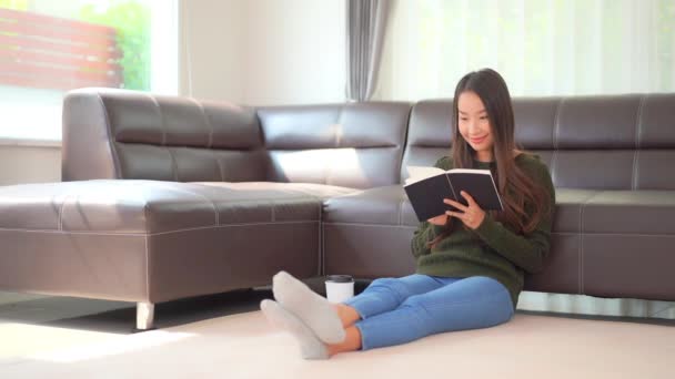 nagranie pięknej azjatyckiej kobiety czytającej książkę w domu - Materiał filmowy, wideo