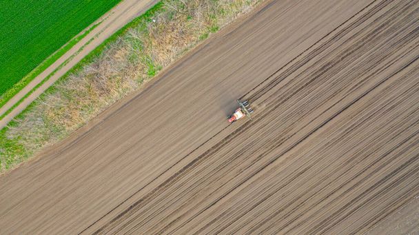 Yläpuolella näkymä, traktorin vetämällä mekaaninen kylvö kone yli pelto, maaperä, istutus uusi vilja sato, maissi, maissi. - Valokuva, kuva