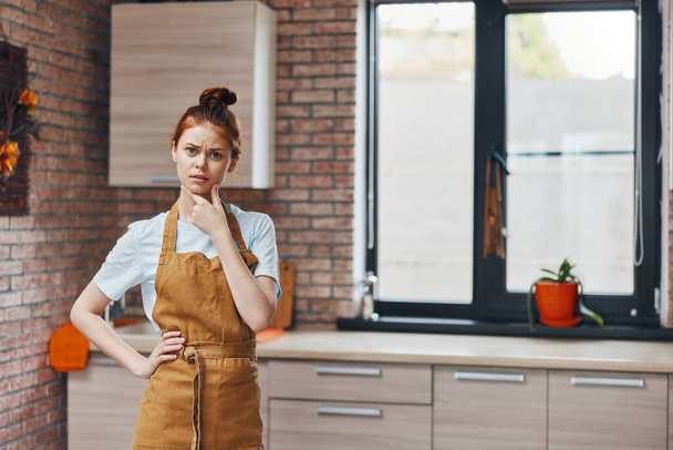 uma dona de casa em um avental gestos com as mãos na cozinha tarefas domésticas casa vida - Foto, Imagem