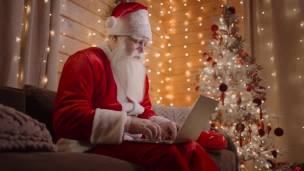 Oldalnézet Mikulás dolgozik laptop küld leveleket kívánságait vagy gratulál e-mailben karácsonyra vagy szilveszterre. Mikulás kommunikál a szociális hálózatok a gyerekekkel a világ minden tájáról. - Felvétel, videó