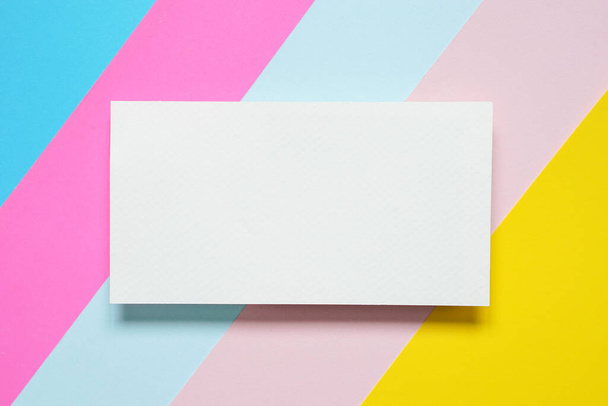 una vista superior de una tarjeta blanca en blanco horizontal sobre un fondo de papel colorido. - Foto, imagen