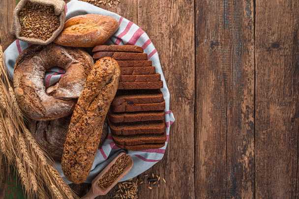 Pan fresco y crujiente de varios tipos en una mesa de madera. Productos de panadería. - Foto, imagen