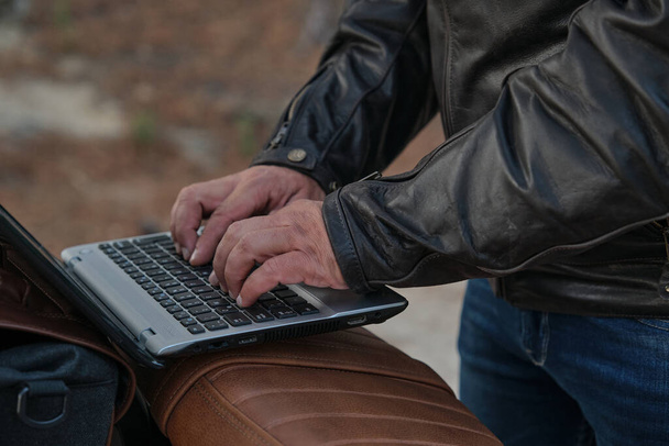 Homme méconnaissable travaillant sur son ordinateur portable tout en conduisant une moto - Photo, image