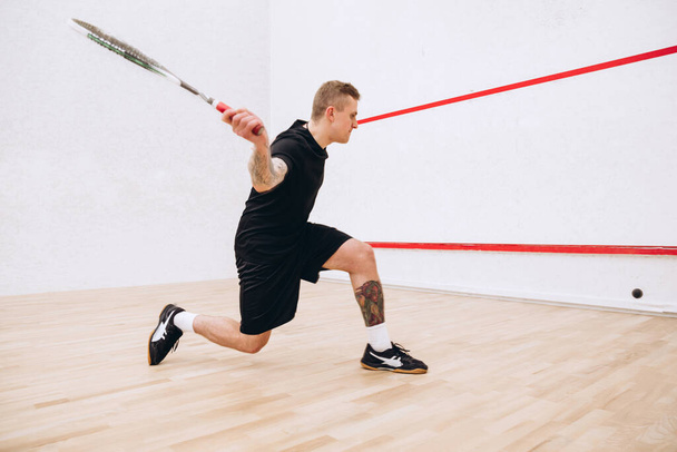 Retrato completo de jovem esportivo em treinamento uniforme preto, jogando squash no estúdio esportivo - Foto, Imagem