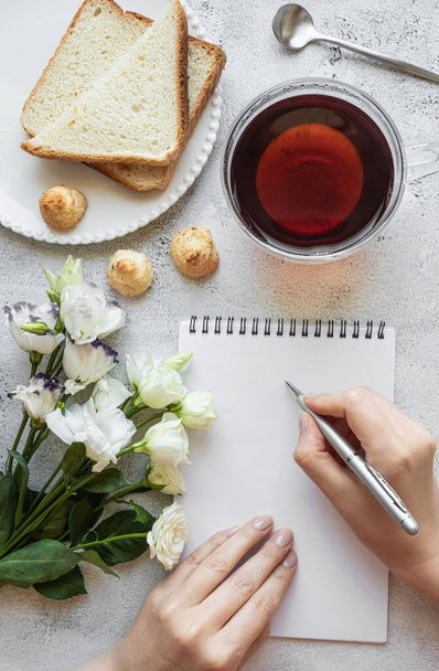 Mani che scrivono su un blocco note, impostazione colazione - Foto, immagini