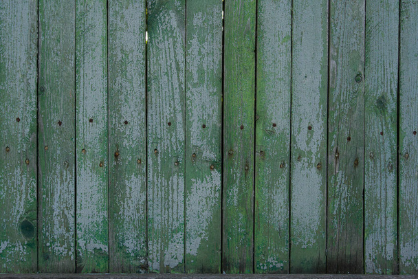 texture of a wooden fence.  fence painted green.  peeling paint on an old fence.  old wood texture.  photo can be used as a photophone, as a texture - Фото, изображение
