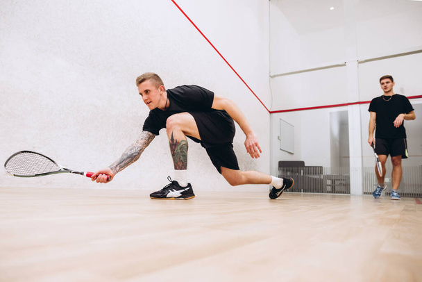 Full-length portrait of two young sportive boys training together, playing squash isolated over sport studio background - Photo, Image